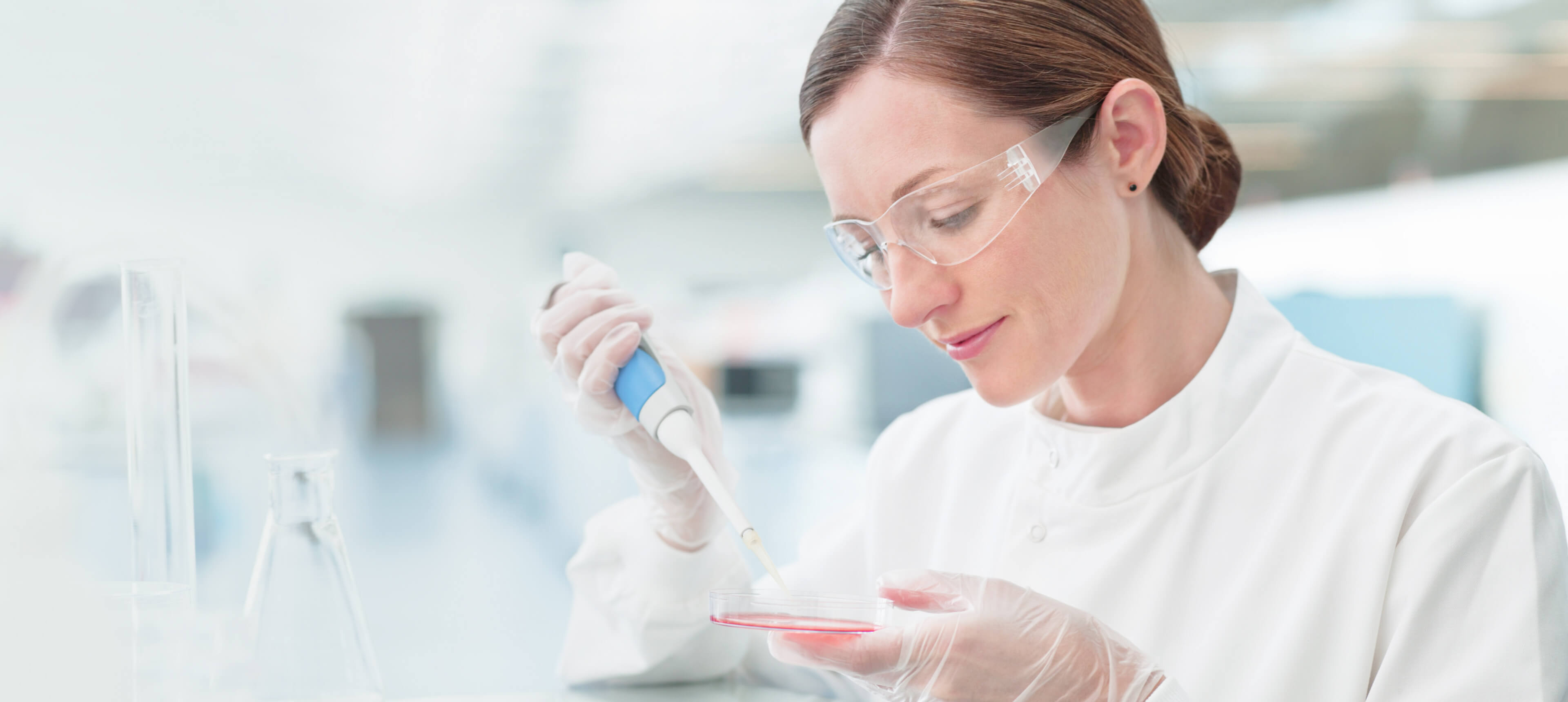 A female scientist in a lab coat holds a test tube, conducting experiments in a laboratory setting.